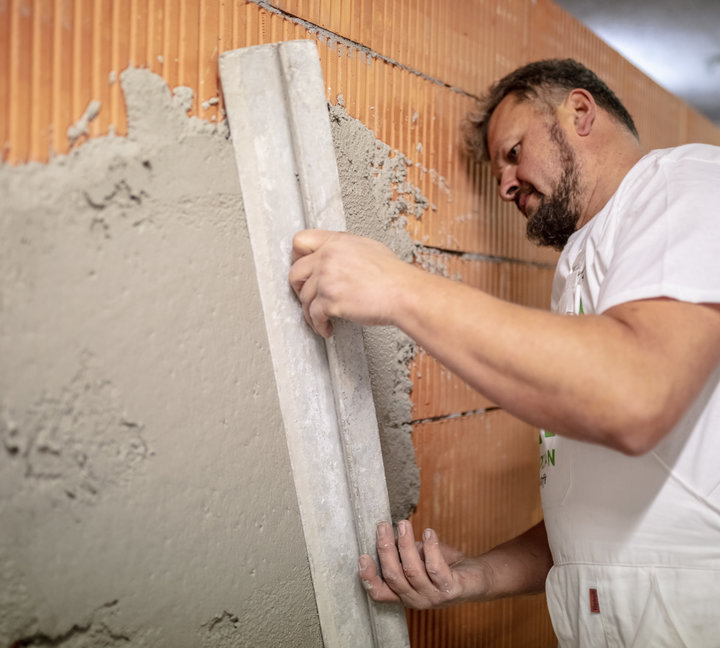 Mann der eine Wand verputzt