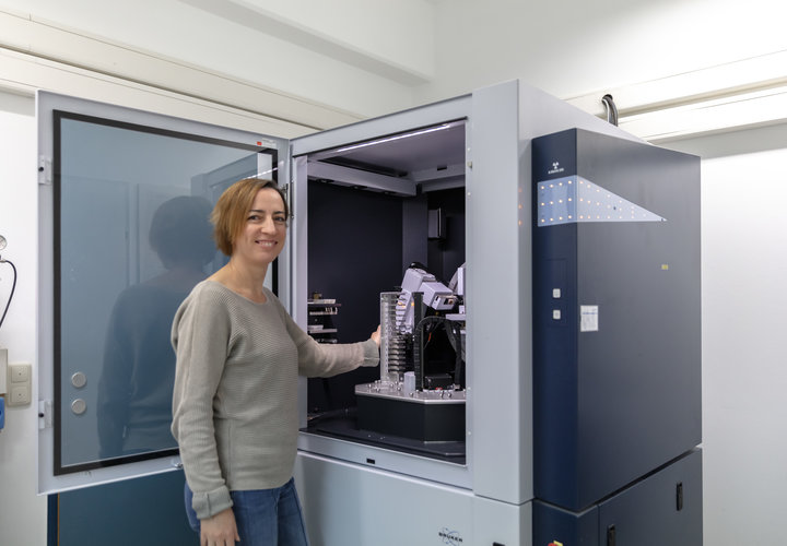 Eine Frau bedient ein gerät im Labor und blickt lächelnd in die Kamera.