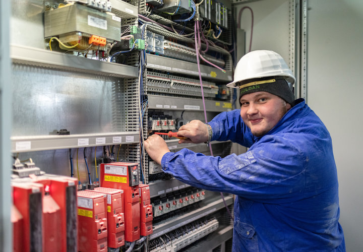 Ein Elektriker in Schutzkleidung bei der Arbeit.